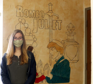 Madisyn Andrade standing in front of her Romeo and Juliet mural in the English hallway. /Alexis Galarza • The Brand