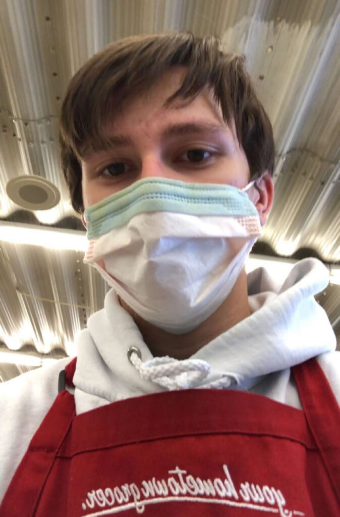 Dylan Perkins at wearing a mask at work at Uptown Market./Courtesy • Dylan Perkins