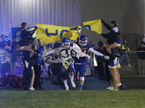 Varsity players run through the homecoming banner. /Ron Espinola • The Brand