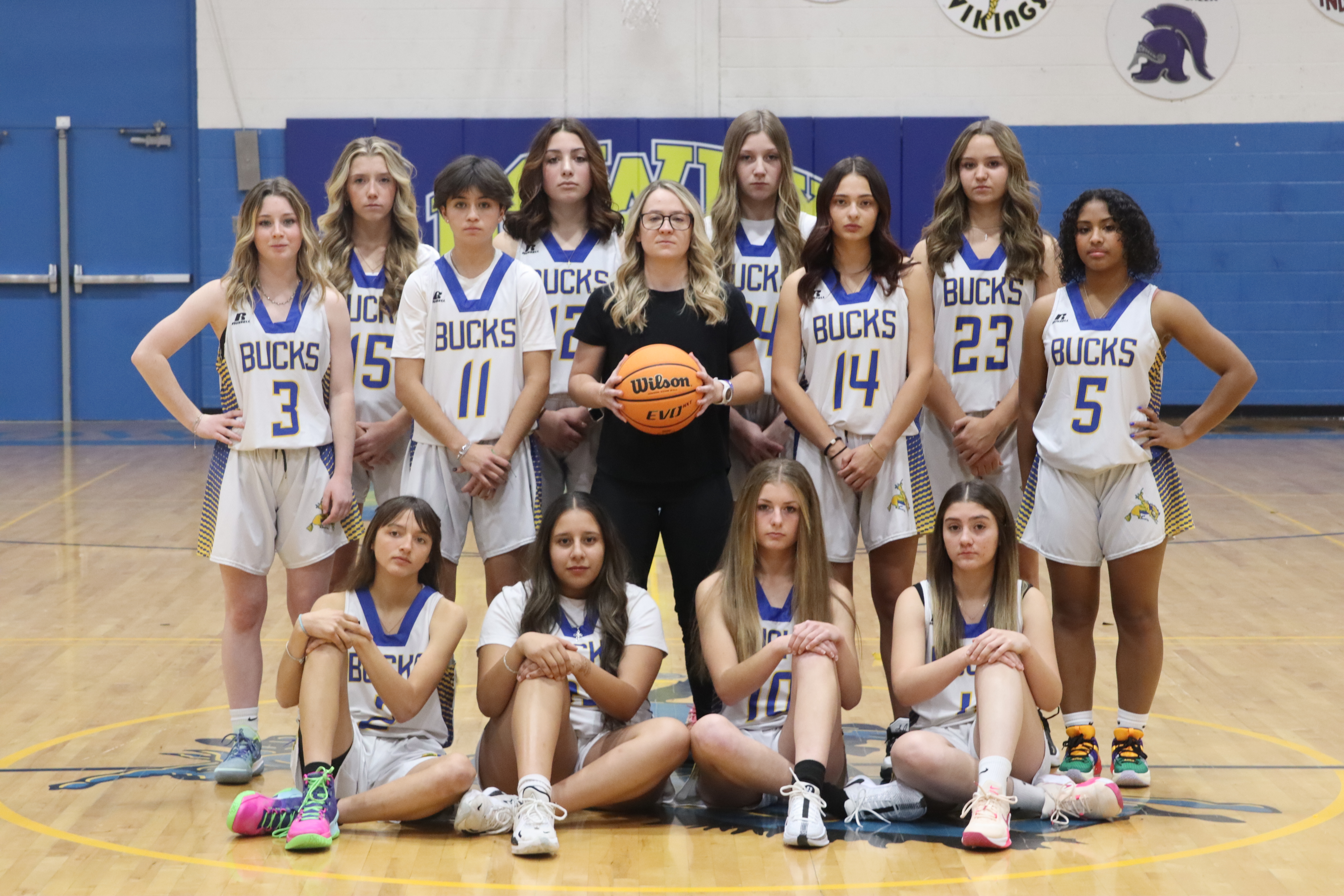 The JV girl’s basketball team smiles with their coach for their team picture./ Olivia Espinola • The Brand