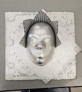 Donna Johnson artwork. A silver mask on a puzzle background. /Courtesy • Julia Topholm