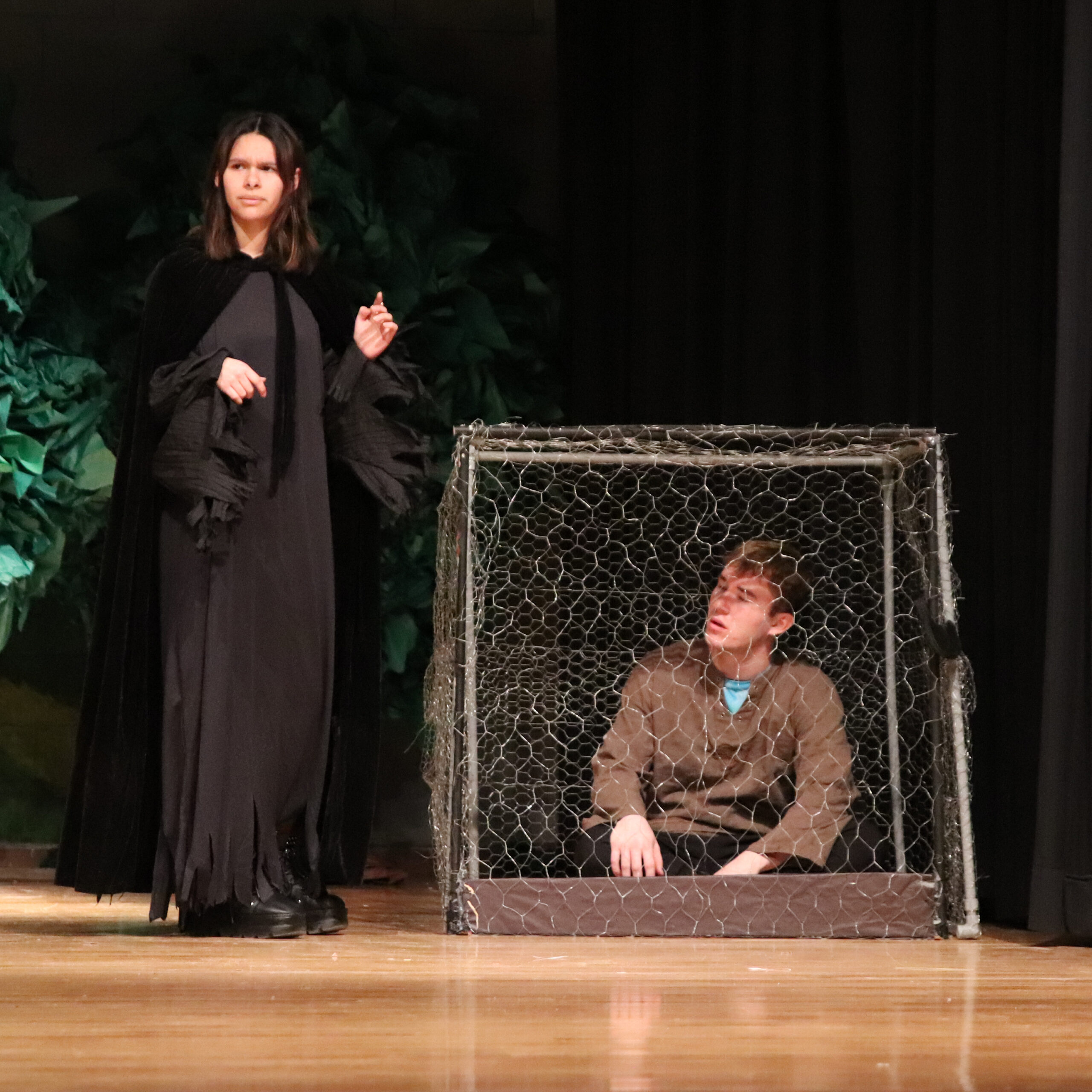 Jacob Woolsey trapped in a cage by Selena Huerta in costume as the Gingerbread Witch / The Brand • Raegan Terry 