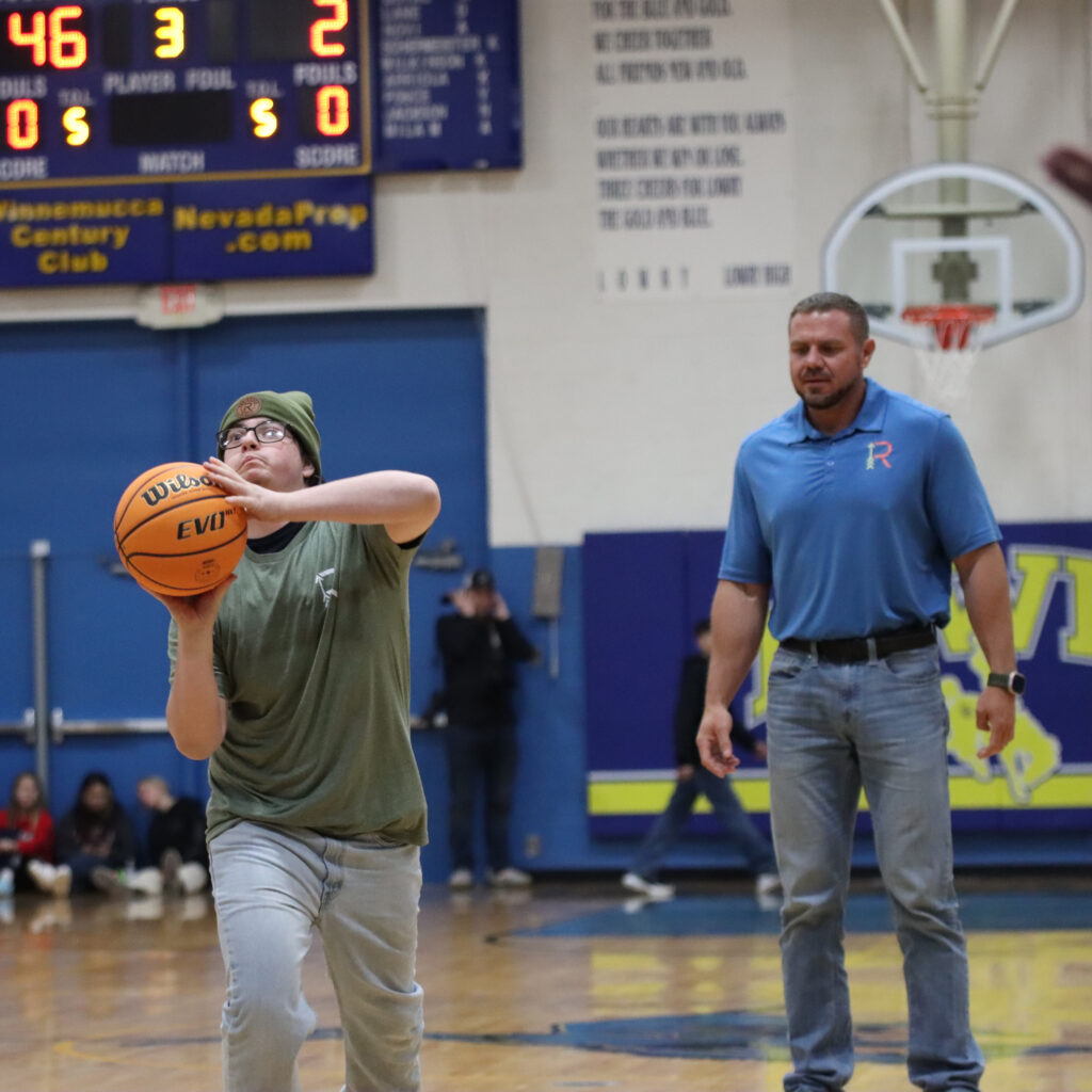 Jeffries Nathan shoots during halftime of a basketball game to win a scholarship sponsored by Waylon Huber (Right) and Robin Hood Realty. /Olivia Espinola • The Brand 